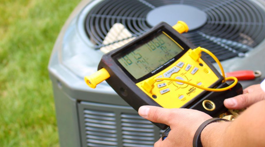 Technician using a digital thermometer on an air conditioning unit for HVAC maintenance by SOS Heating & Cooling.